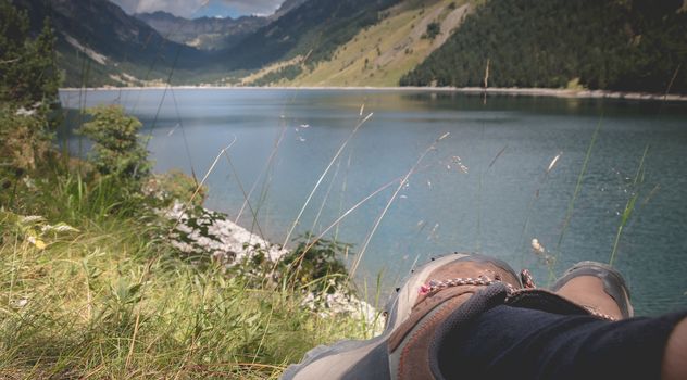 hiker taking a break sitting near the lake of Oule in valley of Aure in Haute-Bigorre in the department of Hautes-Pyrénées in France