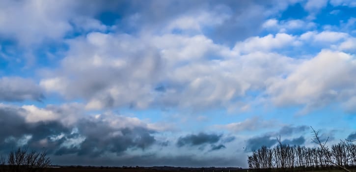 Stunning mixed cloud formation panorama in a deep blue summer sky.