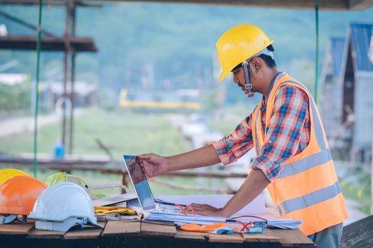 Engineer working with laptop and blueprints,engineer inspection in construction site for architectural plan,sketching a construction project.