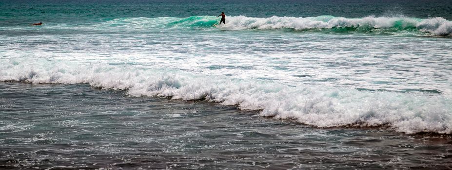 Surfer on a surfboard in the sea water splash blue transparent surf fresh ocean water background island of Bali Indonesia.