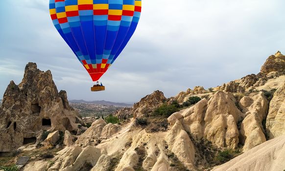 Hot air balloon flying over cave houses of Cappadocia and Goreme valley. Travel concept Turkey. Kapadokya.