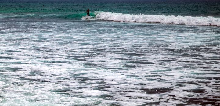 Surfer on a surfboard in the sea water splash blue transparent surf fresh ocean water background island of Bali Indonesia.