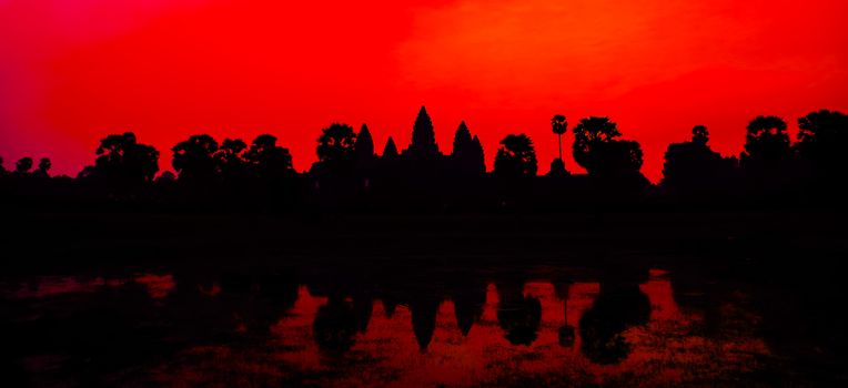 Banner Angkor Wat facade silhouette reflection on water pond on Beautiful colorful red sunrise sky background Palm trees. Famous landmark Angkor Wat complex khmer culture Siem Reap Cambodia