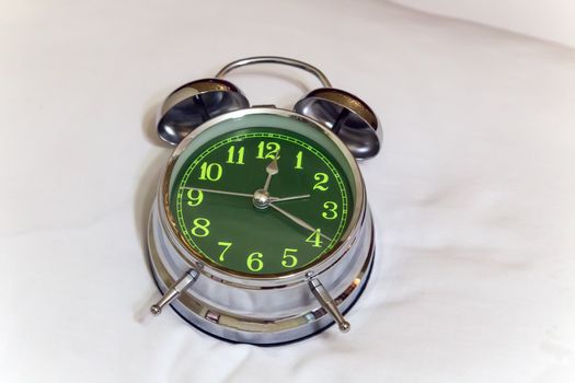 Sleeping alarm clock green on the bed in bedroom Close-up view