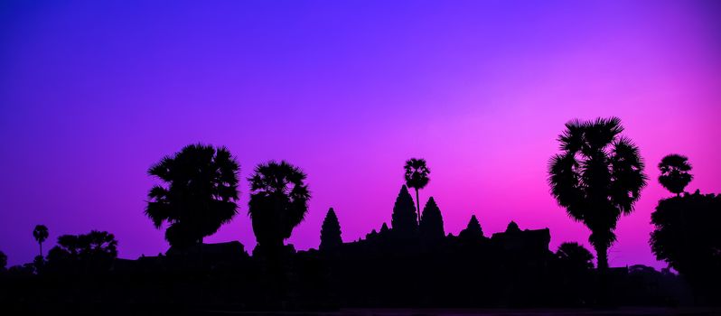Panorama Palm trees Mist sunrise tropical morning violet tourist attraction ancient temple facade silhouette of the Angkor Wat temple in Angkor Archaeological Park near Siem Reap in Cambodia.