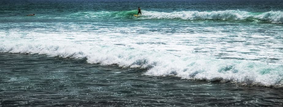 Surfer on a surfboard in the sea water splash blue transparent surf fresh ocean water background island of Bali Indonesia.