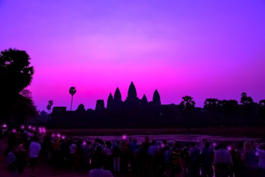 Tourist taking picture smartphone Angkor Wat temple Panorama Mist sunrise tropical morning violet on water pond sky background. Holy place in Asain. Popular tourist attraction ancient temple.