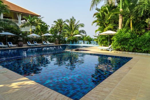 Blue pool. Tropical beach relax deck chairs sun umbrella. Hotel resort - travel vacation.