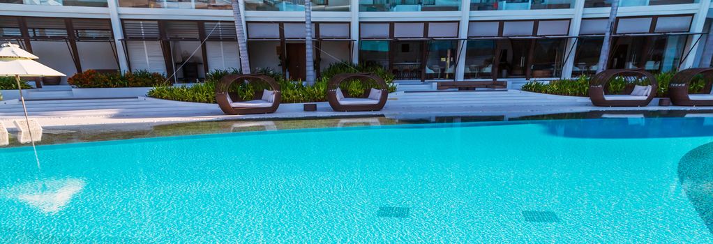 tropical resort hotel with swimming pool. Beach umbrella, beach chair tile floor marble ceramic mosaic. Vacation and travel concept.