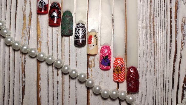 A palette of nail designs of different colors with gel polish on a white background. A collection of plastic testers for nail polish.