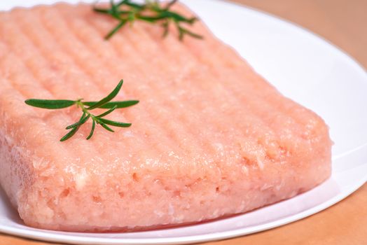 Raw Minced meat with herbs and spices,minced chicken close-up. Raw chicken mince on a white plate and on a white background. Close-up of chicken mince. Delicious diet meat.