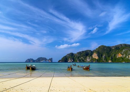 Cruse liner in sea. Thai traditional wooden longtail boat in sand beach island Thailand.