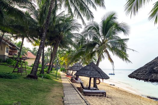 Tropical views from Long Beach Phu Quoc Island, Vietnam. Nobody on the beach. Palm tree bamboo umbrellas and sun chairs in background. scene vacation and summer holiday concept.