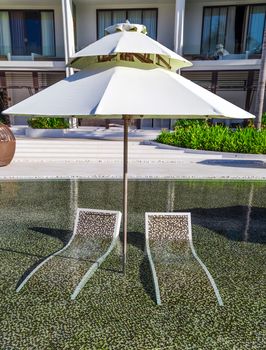 tropical resort hotel with swimming pool. Beach umbrella, beach chair tile floor marble ceramic mosaic. Vacation and travel concept.