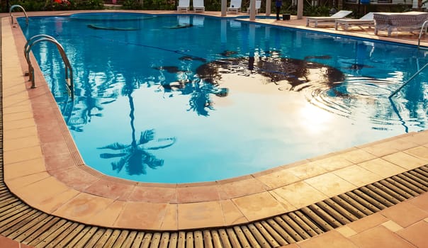 Swimming pool luxury tropical resort panoramic. Sunbathing deck sun loungers relaxing seats and sun umbrella.