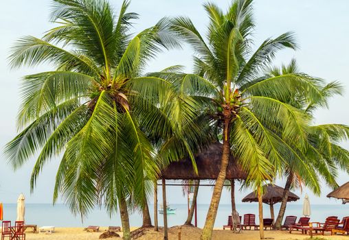 Tropical views from Long Beach Phu Quoc Island, Vietnam. Nobody on the beach. Palm tree bamboo umbrellas and sun chairs in background.