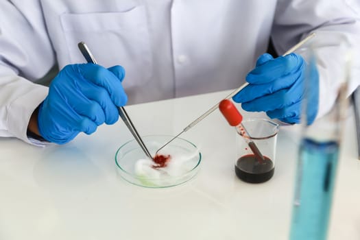 Professional doctor scientist wearing blue rubber gloves using needle and forceps to research in working laboratory with glassware.  Science and Healthcare, Coronavirus (Covid-19) Protection Concept.