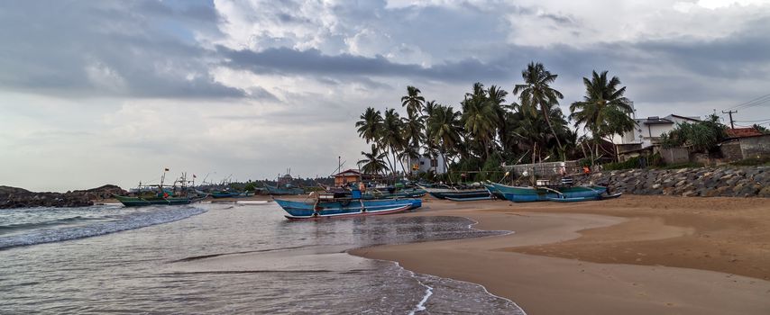 Sri Lankan traditional fishing catamarans, Colorful fishing boats on a long sandy beach on the ocean coast of Sri Lanka. Popular landmark fishing