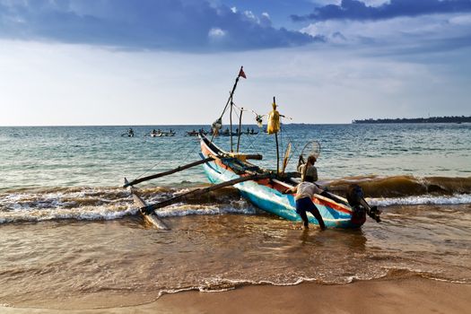Sri Lankan traditional fishing catamaran Colorful fishing boats on a long sandy beach on the ocean coast of Sri Lanka. fishing Ceylon village.