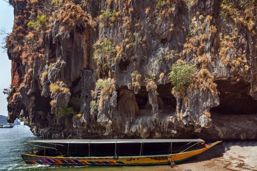 Traditional old thai long-tail boat on beach island in andaman sea, cave limestone rock, Phuket, Krabi, Khao Phing Kan Pang Nga bay, South of Thailand.