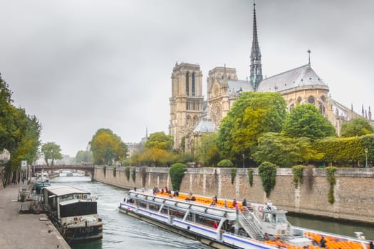 Paris, France - May 8, 2017 - Side view of Notre Dame Cathedral on the Seine with barges on a spring day