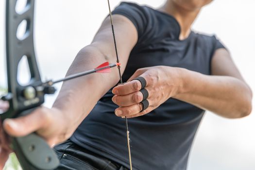 attractive spot woman stretching a bow string with an arrow on archery.