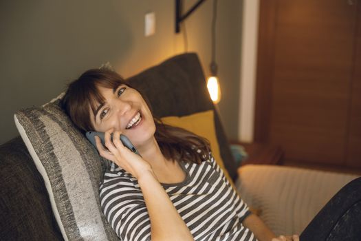 Woman on her bedroom, having a great chat at phone