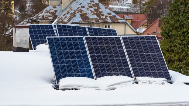 Solar panels of photovoltaic power plant on the snow covered roof