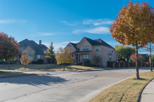 New development neighborhood with row of two story houses clean concrete sidewalk with colorful fall foliage outside Dallas, Texas, America