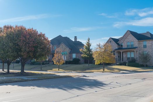 New development neighborhood with row of two story houses clean concrete sidewalk with colorful fall foliage outside Dallas, Texas, America