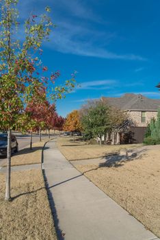 Front porch entrance of new development houses with parked car on residential street suburbs Dallas, Texas, America. Colorful fall foliage under sunny blue cloud sky.