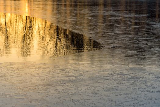 Natural winter background made of half frozen lake at sunset