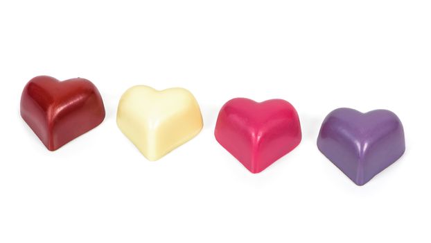 Colorful heart shaped chocolates in a row isolated on white background with clipping path