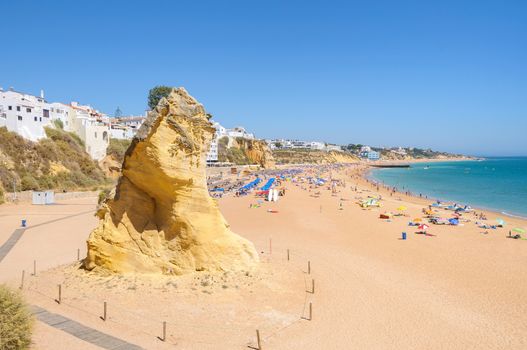 View of sunny public beach with sandstone rock in Albufeira, Algarve, Portugal