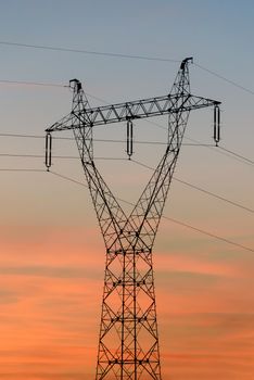 Closeup of electricity pylon and high voltage power lines at sunset