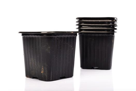 used black plastic gardening bucket waiting for spring on white background in studio