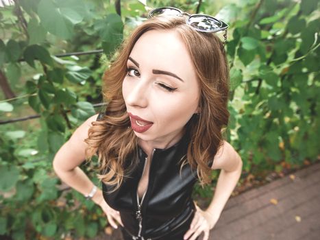 Close-up of a positive flirtatious European woman. The girl smiles happily, blinks playfully at the camera, flirts with you. Facial expressions and human emotions. nature