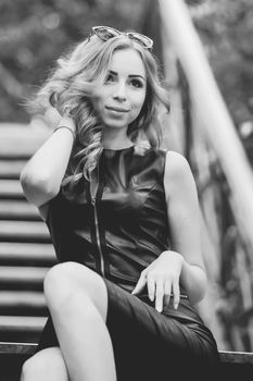 Portrait of curly woman in black dress sitting on a street