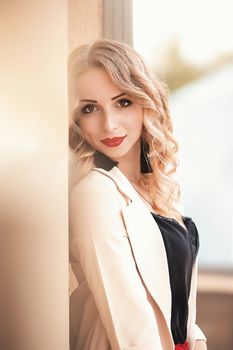 Beautiful young girl standing near the stone wall. Portrait pretty young fashion girl near a stone wall. Beautiful blonde woman with long hair posing near a stone wall.