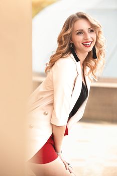 Beautiful young girl standing near the stone wall. Portrait pretty young fashion girl near a stone wall. Beautiful blonde woman with long hair posing near a stone wall.