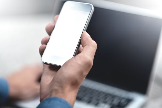 Cropped image of young woman downloading applications and multimedia programs by mobile smartphone, with laptop computer at street in modern city.