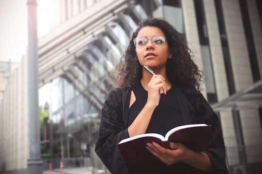 Self employed mixed race female entrepreneur busy writing in her notebook