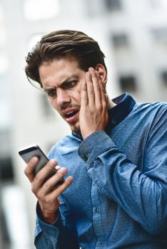 Sad caucasian businessman in glasses dressed at casual wear standing at the street.