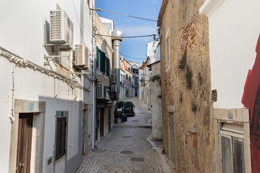 Sesimbra, Portugal - February 20, 2020: View of the city center of Sesimbra by the sea where people are walking on a winter day