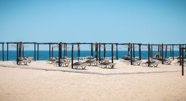 Tavira Island, Portugal - May 3, 2018: View of deckchairs and umbrellas stored on the fine sandy beach sand on a spring day