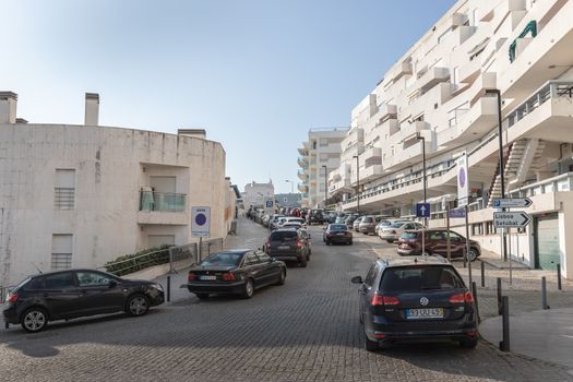 Sesimbra, Portugal - February 20, 2020: View of the city center of Sesimbra by the sea where people are walking on a winter day