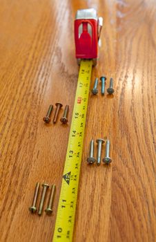 4 sets of 3 screws and a tape measure on wood