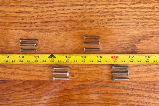 4 sets of 3 screws and a tape measure on wood