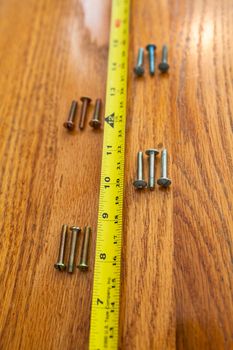 4 sets of 3 screws and a tape measure on wood