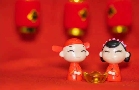 Chinese New Year decoration on a red background Chinese Couple Figure Model wish for a Luck  and lump of gold and a Chinese Word on Lantern said Luck